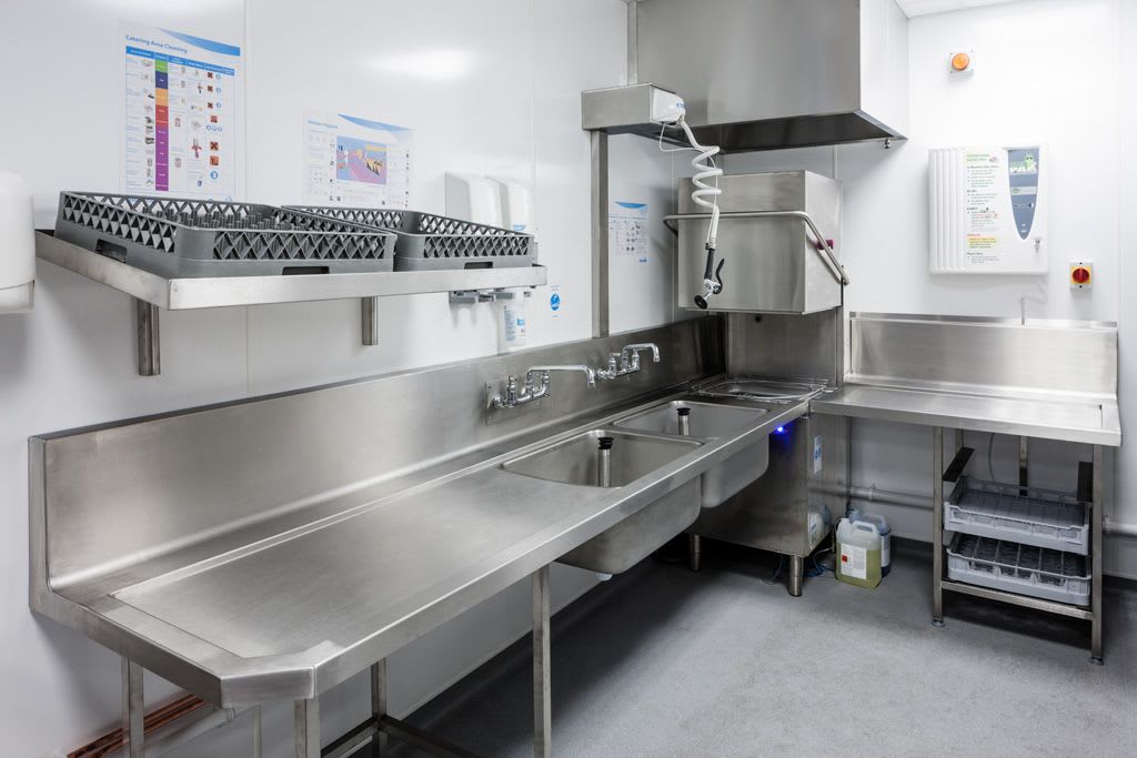 A professionally designed commercial kitchen dishwashing area with stainless steel equipment and organized dish racks
